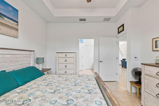 tiled bedroom featuring ceiling fan and a tray ceiling