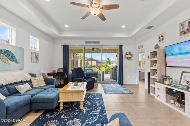 living room with a raised ceiling, a wealth of natural light, ceiling fan, and light tile patterned flooring