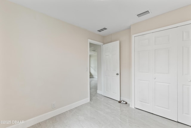 unfurnished bedroom with a closet, visible vents, marble finish floor, and baseboards