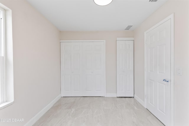 unfurnished bedroom featuring multiple closets, visible vents, baseboards, and multiple windows