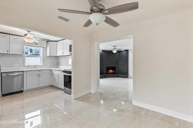 kitchen with visible vents, electric stove, light countertops, a brick fireplace, and stainless steel dishwasher