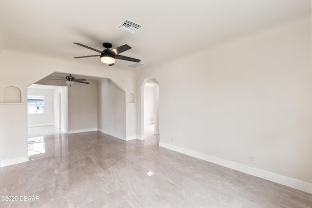 unfurnished room featuring arched walkways, marble finish floor, visible vents, ceiling fan, and baseboards