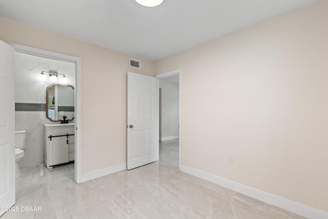 unfurnished bedroom featuring marble finish floor, baseboards, visible vents, and connected bathroom