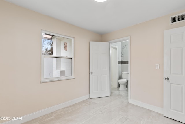 unfurnished bedroom featuring baseboards, visible vents, and ensuite bathroom