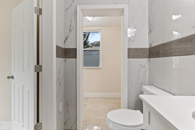 bathroom with vanity, toilet, and tile walls