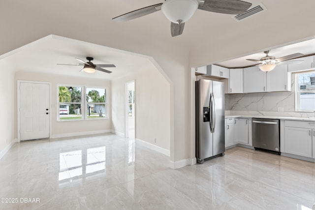 kitchen with marble finish floor, stainless steel appliances, light countertops, visible vents, and decorative backsplash