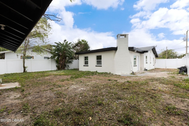 rear view of property with a chimney and a fenced backyard