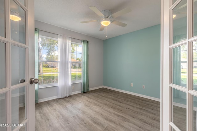 unfurnished room featuring wood finished floors, a ceiling fan, and baseboards
