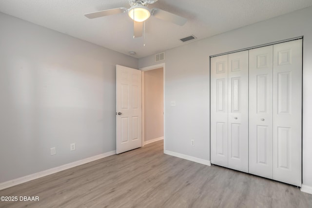 unfurnished bedroom with a closet, light wood-style flooring, visible vents, and baseboards