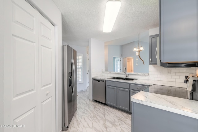 kitchen featuring marble finish floor, stainless steel appliances, backsplash, gray cabinets, and a sink
