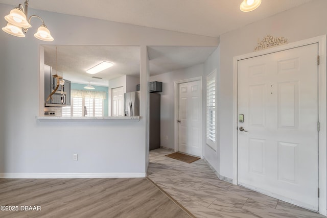 entrance foyer with baseboards, marble finish floor, and a chandelier