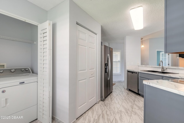 laundry area featuring marble finish floor, laundry area, a sink, a textured ceiling, and washer / clothes dryer
