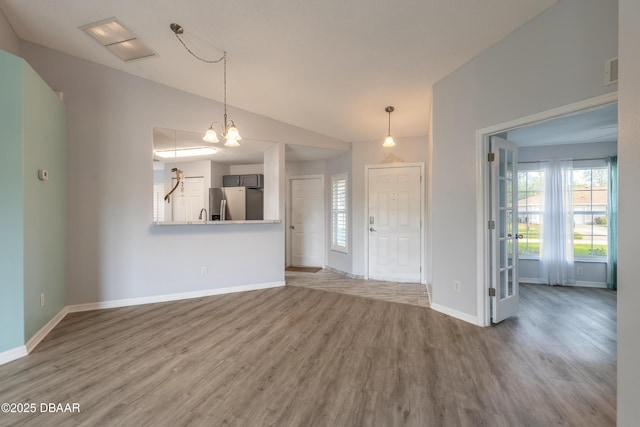 unfurnished living room featuring lofted ceiling, wood finished floors, visible vents, and baseboards