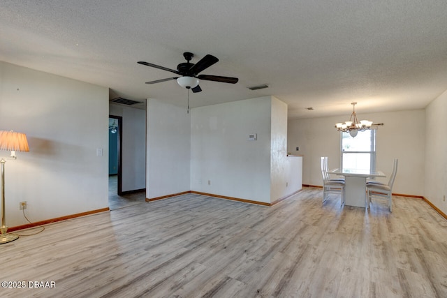 empty room featuring ceiling fan with notable chandelier, light hardwood / wood-style floors, and a textured ceiling