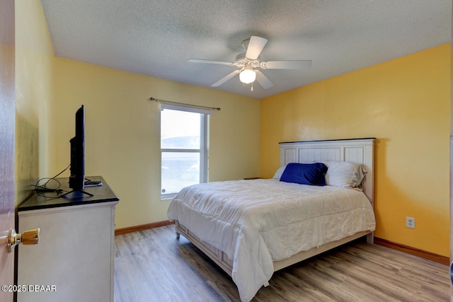 bedroom with ceiling fan, a textured ceiling, and light hardwood / wood-style flooring