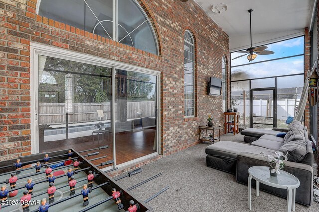 interior space featuring carpet flooring, a healthy amount of sunlight, a high ceiling, and brick wall