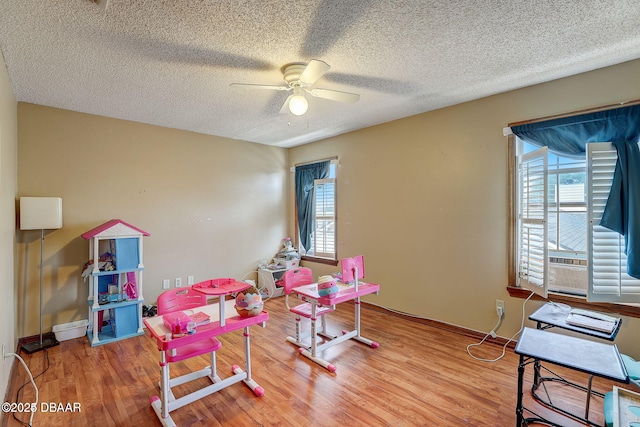 game room featuring ceiling fan, a textured ceiling, and wood finished floors