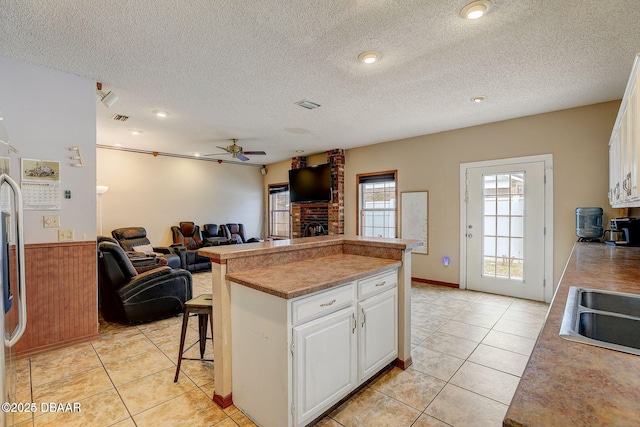 kitchen featuring light tile patterned floors, a kitchen island, white cabinets, and open floor plan