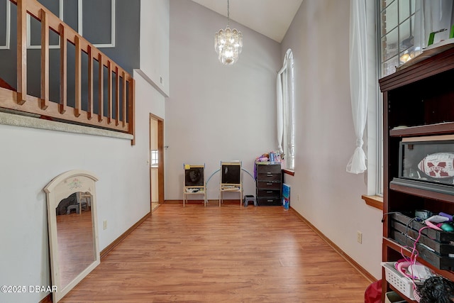 interior space with high vaulted ceiling, a notable chandelier, baseboards, and wood finished floors