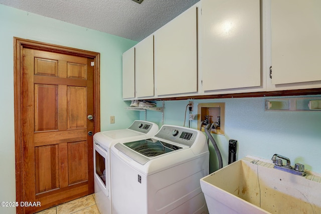 laundry area featuring light tile patterned floors, cabinet space, a sink, a textured ceiling, and washer and dryer