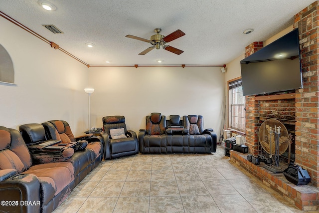 living area featuring a fireplace, light tile patterned floors, visible vents, a ceiling fan, and a textured ceiling