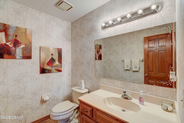 bathroom featuring a textured ceiling, vanity, and toilet