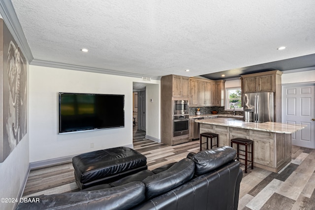 living room featuring light hardwood / wood-style floors, a textured ceiling, and crown molding