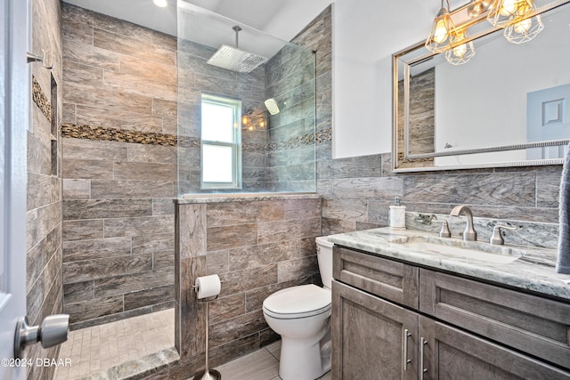 bathroom with tiled shower, toilet, tile walls, tile patterned flooring, and vanity