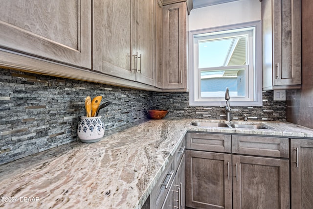 kitchen featuring decorative backsplash, sink, and light stone counters