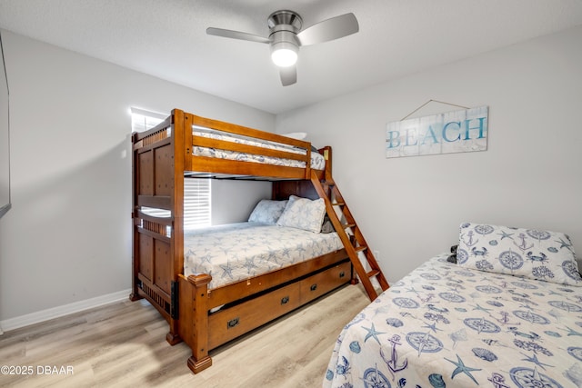 bedroom with a ceiling fan, wood finished floors, baseboards, and a textured ceiling