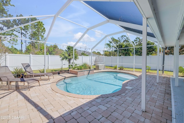 view of swimming pool featuring glass enclosure, a patio, and a fenced backyard