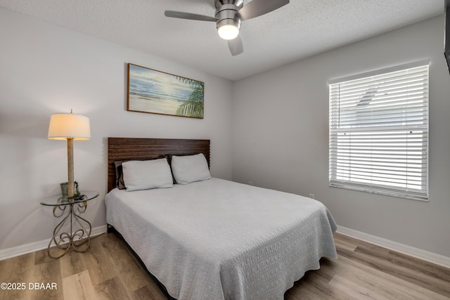 bedroom with baseboards, a textured ceiling, wood finished floors, and a ceiling fan