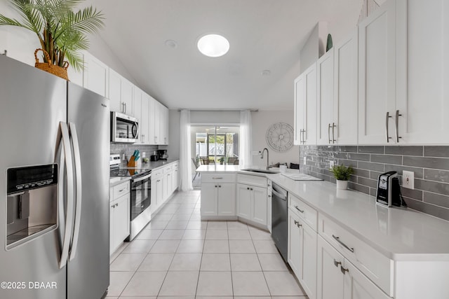 kitchen featuring light countertops, light tile patterned floors, appliances with stainless steel finishes, a peninsula, and a sink