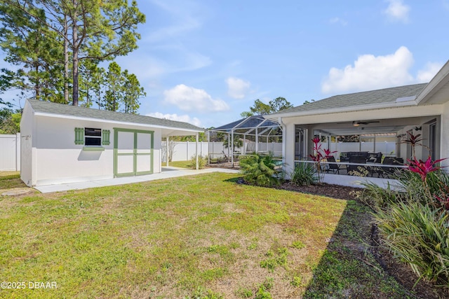 rear view of property featuring a yard, a fenced backyard, ceiling fan, an outdoor structure, and a patio area