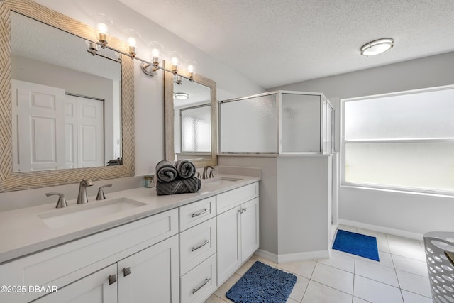 bathroom with tile patterned flooring, a stall shower, double vanity, and a sink