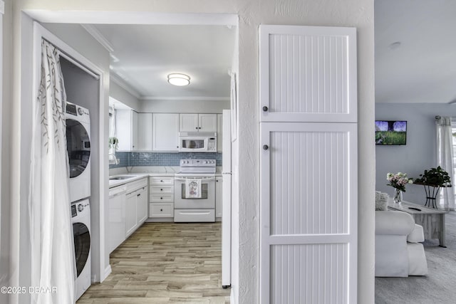 1101 Ocean Marina Dr Unit 201, Flagler Beach, FL 32136 - washroom with stacked washer / dryer, ornamental molding, plenty of natural light, light wood finished floors, and a sink