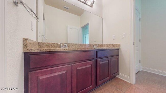 bathroom featuring double vanity, baseboards, visible vents, tile patterned flooring, and a sink