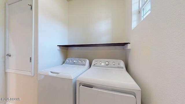 washroom featuring laundry area, a textured wall, and separate washer and dryer