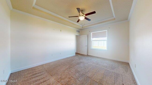 carpeted spare room featuring baseboards, a raised ceiling, a ceiling fan, and ornamental molding