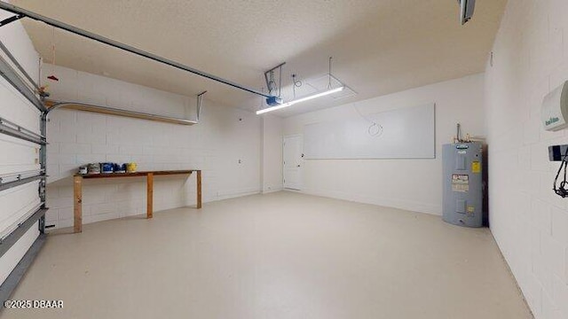 garage featuring a garage door opener, concrete block wall, and electric water heater