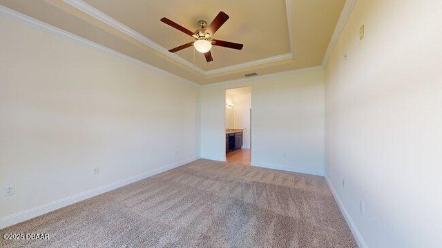 unfurnished bedroom with carpet floors, visible vents, baseboards, a tray ceiling, and crown molding