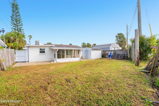 rear view of property with a lawn and a sunroom