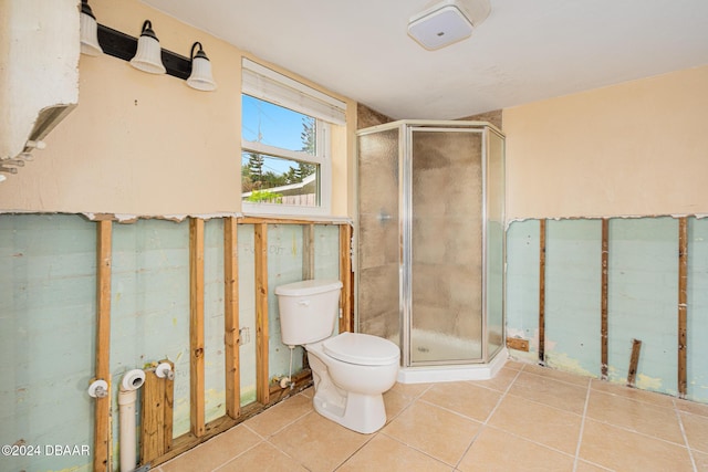 bathroom featuring tile patterned floors, toilet, and a shower with door