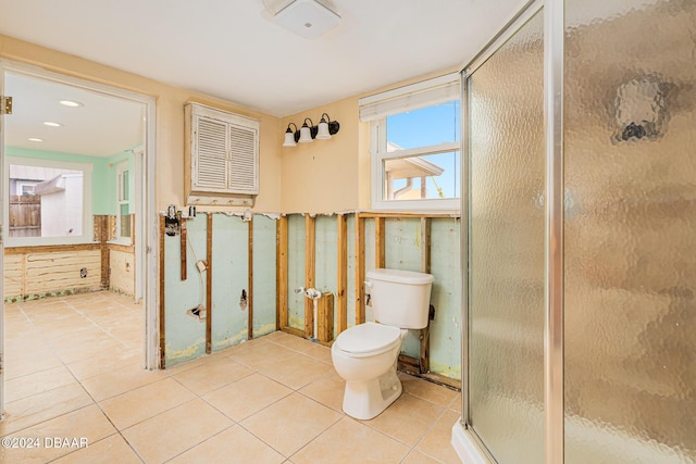 bathroom featuring tile patterned flooring, toilet, and a shower with shower door