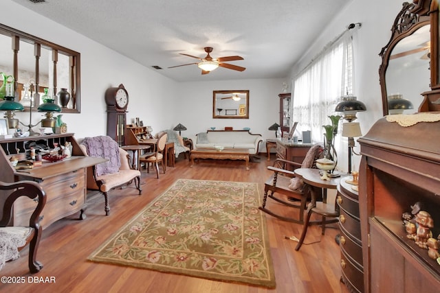 living area featuring ceiling fan, hardwood / wood-style floors, and a textured ceiling