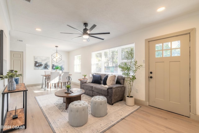 living room with a textured ceiling, light wood-type flooring, ceiling fan, and a healthy amount of sunlight