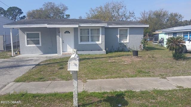 bungalow-style home with stucco siding, driveway, and a front yard