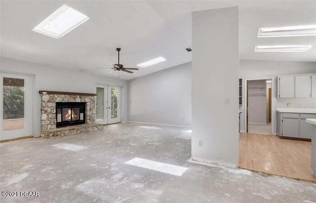 21305 86th Ave, Micanopy, FL 32667 - unfurnished living room featuring lofted ceiling, healthy amount of natural light, a stone fireplace, ceiling fan, and a skylight