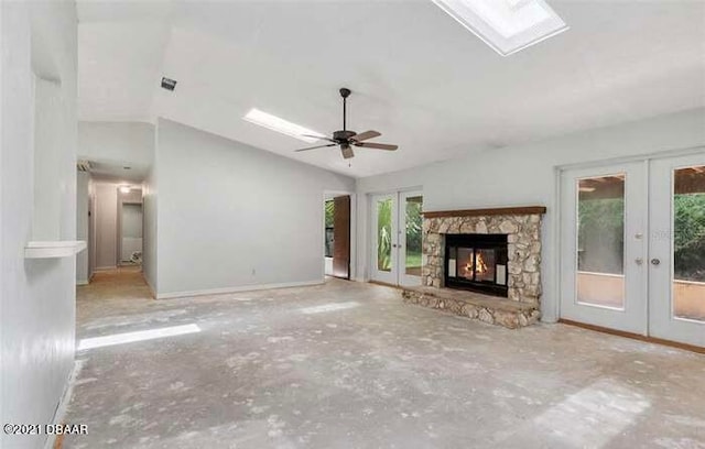 unfurnished living room with a stone fireplace, lofted ceiling, french doors, and ceiling fan