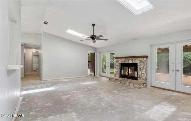 21305 86th Ave, Micanopy, FL 32667 - unfurnished living room featuring french doors, vaulted ceiling, a fireplace, a ceiling fan, and a skylight